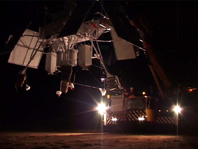 NIGHTGLOW hanging from a crane at night