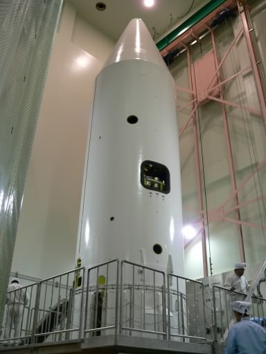 The white cylindrical nose fairing, conical at the top, has three circular holes and two rectangular ones visible. (37K JPEG)