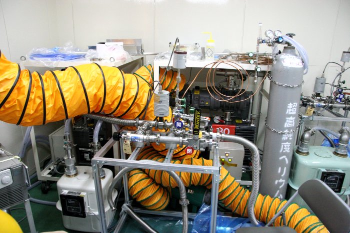 bright yellow-orange plastic ducts, 30 centimeters in diameter, drape themselves over the stark aluminum gridwork of a vaccuum manifold support system, while a heavy dark pump lurks just behind. (90K JPEG)