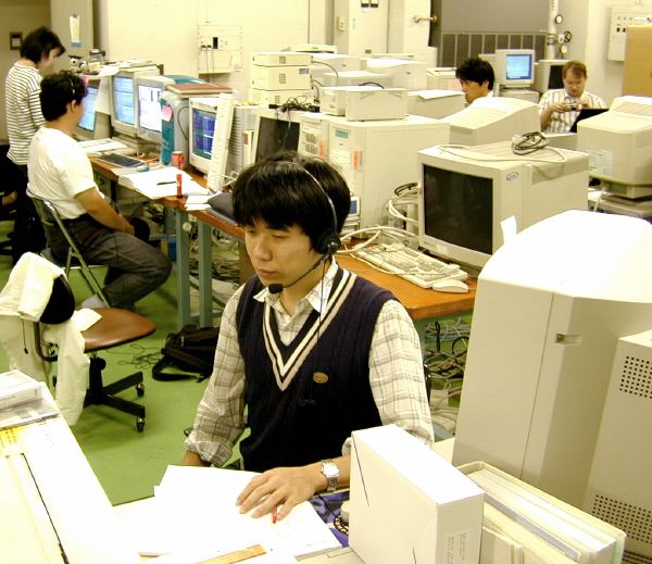 Fujimoto-san at the command workstation, wearing headset (59K JPEG)