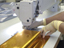 Worker using machine to sew gold-colored blanket