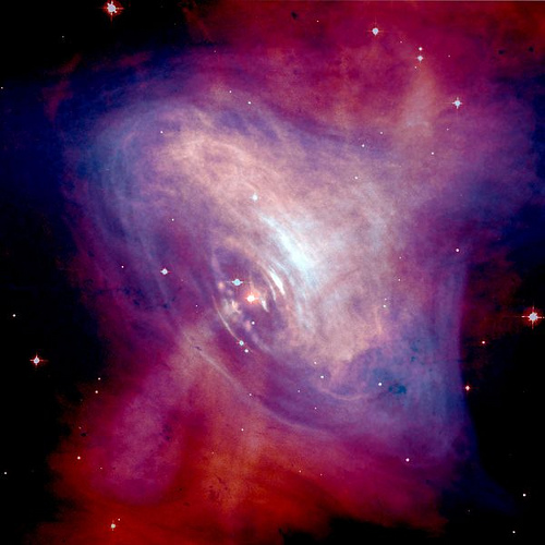 A composite image of the Crab Nebula showing the X-ray (blue), and optical (red) images superimposed. The size of the X-ray image is smaller because the higher energy X-ray emitting electrons radiate away their energy more quickly than the lower energy optically emitting electrons as they move.  Credit: Optical: NASA/HST/ASU/J. Hester et al. X-Ray: NASA/CXC/ASU/J. Hester et al.